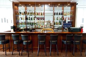 a bar with stools in a room with bottles of alcohol at Stern Hotel Hannover in Hannover