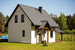 PłaskaBiały Domek Sucha Rzeczka的一座黑色屋顶的白色小房子