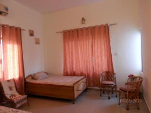 a small bedroom with a bed and two chairs at Sariska Farms in Tehla +38 photos