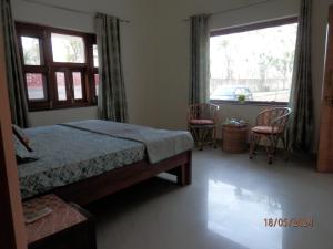 a bedroom with a bed and two chairs and a window at Sariska Farms in Tehla
