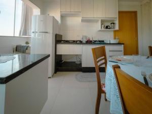 a kitchen with a table and a white refrigerator at Apartamento perto UEM Wi-Fi MN701 in Maringá