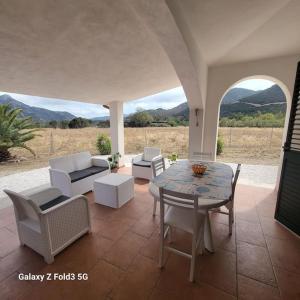 un patio con mesa y sillas y vistas a las montañas en Elisabeth's House, en Villaputzu