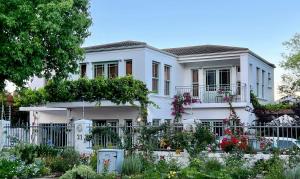 a white house with flowers in front of it at Penelope's Stellenbosch in Stellenbosch