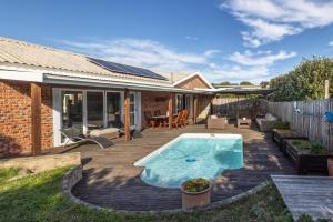 a backyard with a swimming pool on a wooden deck at Delightfully Casual & Spacious in Cape St Francis
