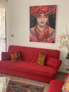 eine rote Couch in einem Wohnzimmer mit einem Gemälde einer Frau in der Unterkunft Residence Corona Grossa Balangero in Balangero