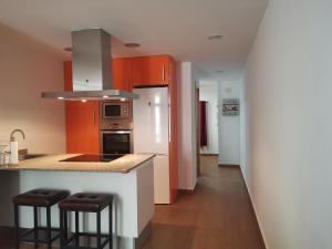 a kitchen with orange cabinets and a counter with stools at Apartamento centrico en Calella in Calella