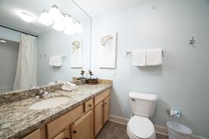 a bathroom with a sink and a toilet and a mirror at The Oasis At Orange Beach 2215 by Liquid Life in Orange Beach