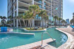 a swimming pool with palm trees in front of a building at The Oasis At Orange Beach 2215 by Liquid Life in Orange Beach