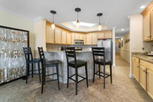 a kitchen with a bar with black stools at The Oasis At Orange Beach 2215 by Liquid Life in Orange Beach