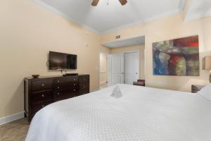 a bedroom with a white bed and a flat screen tv at The Oasis At Orange Beach 2215 by Liquid Life in Orange Beach