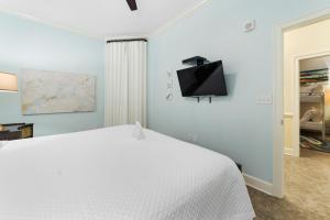 a bedroom with a white bed and a tv on the wall at The Oasis At Orange Beach 2215 by Liquid Life in Orange Beach