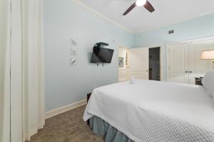 a bedroom with a white bed and a ceiling fan at The Oasis At Orange Beach 2215 by Liquid Life in Orange Beach