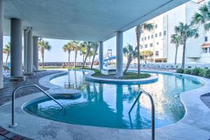 a swimming pool with palm trees and a building at The Oasis At Orange Beach 2215 by Liquid Life in Orange Beach