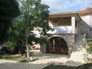 a stone house with a door and a tree at Apartman Iris in Gabonjin