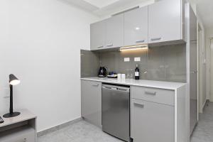a kitchen with white cabinets and a stainless steel dishwasher at Argus Hotel Darwin in Darwin