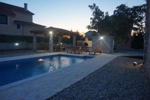 a swimming pool with two benches next to a house at Apartman Iris in Gabonjin