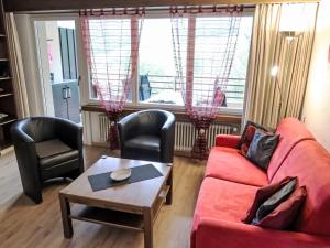 a living room with a red couch and two chairs at Apartment Ringstrasse - Utoring-38 by Interhome in Leukerbad