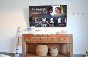 a tv hanging on a wall above a wooden table at The Oasis El Medano, by Nivariahost in El Médano +45 photos