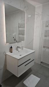 a white bathroom with a sink and a mirror at Orange Apartment in Sarajevo +74 photos