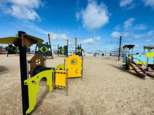 a playground on a sandy beach with a swing set at Appartement vue mer in Calais