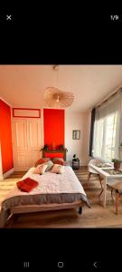 a bedroom with orange walls and a bed and a table at Appartement vue mer in Calais