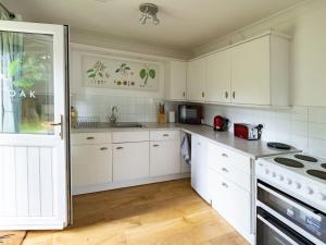a kitchen with white cabinets and a stove top oven at Holiday Home Oak Cottage by Interhome in Shermanbury