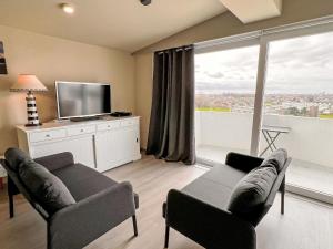 a living room with a couch and a tv at Studio High in the sky with amazing views by Interhome in De Haan