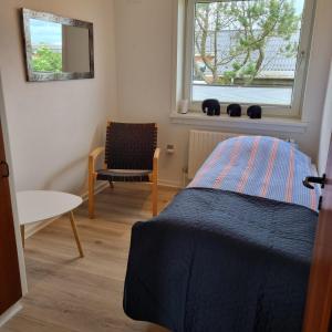 维泽桑讷House in Hvide Sande Centrum的一间卧室，里面有一张床、一把椅子和一扇窗户