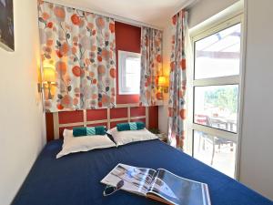 a bedroom with a blue bed with a newspaper on it at Apartment L'Esquinade - FH205 by Interhome in Agay - Saint Raphael