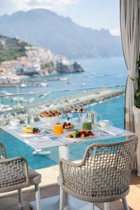 a table with food and a view of the ocean at Hotel Miramalfi in Amalfi