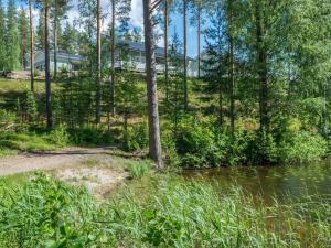ein Haus im Wald neben einem Gewässer in der Unterkunft Holiday Home Saunaharju 3 by Interhome in Kolinkylä