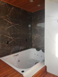 a bath tub in a bathroom with a marble wall at Urubici Maravilhas da Serra 2 in Urubici +9 photos