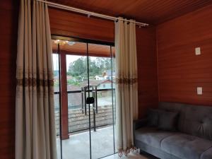 a living room with a couch and a large window at Urubici Maravilhas da Serra 2 in Urubici +3 photos