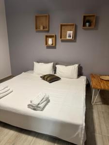 a bed with white sheets and a phone on it at Isalos Suites in Néa Péramos