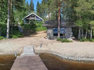 a cabin on the shore of a lake with a dock at Holiday Home Kokkoranta by Interhome in Ilomantsi