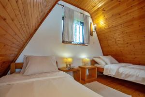 ヴェリカ・プラナにあるChalet Velebitska Kućaのベッド2台と窓が備わる屋根裏部屋です。