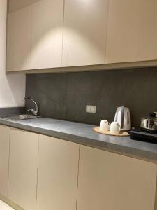 a kitchen with white cabinets and a counter top at Gardens Hotel in Amman