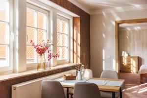 a dining room with a table and chairs and windows at Gut Beinrode in Kallmerode
