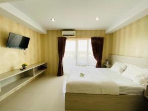 a bedroom with a bed and a tv on the wall at TheTra Homestay in Sunggal
