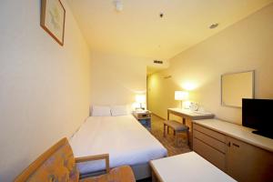 a hotel room with a bed and a desk and a tv at Asahikawa Toyo Hotel in Asahikawa