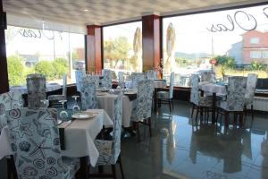 a dining room with tables and chairs and windows at 9 Olas in A Lanzada