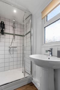 a white bathroom with a sink and a shower at Maple House - Park View Sleeps 7 in Exeter