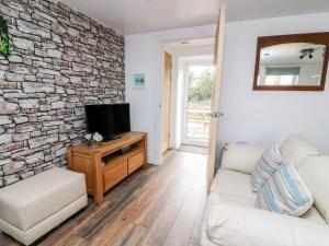a living room with a tv on a stone wall at Field View in Llanybydder
