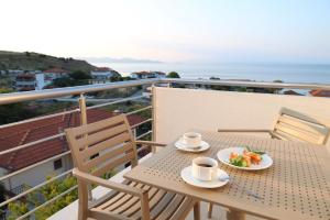 a table with two cups and a plate of food on a balcony at Molon Lave in Nea Roda