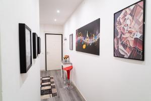 un couloir avec des œuvres d'art sur les murs et un tabouret rouge dans l'établissement Casa vacanze Dream&Fly, à Crémone