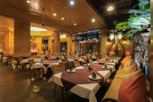 a restaurant with tables and chairs in a room at Sawasdee Village in Kata Beach