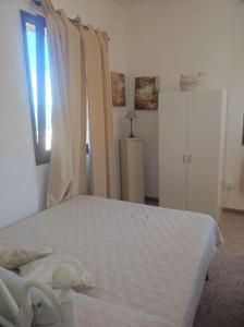 a bedroom with a white bed and a window at Mono Lu Lioni in Lu Lioni
