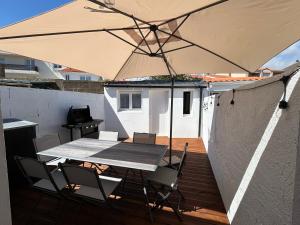 a table and chairs with an umbrella on a deck at Belle petite maison proche de la mer in Les Sables-dʼOlonne
