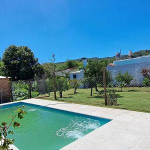een groot zwembad in een tuin met een hek bij Casa Cedrón in La Cumbre