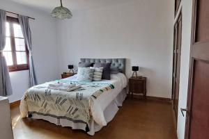 een slaapkamer met een groot bed in een witte kamer bij Casa Cedrón in La Cumbre +19 foto's